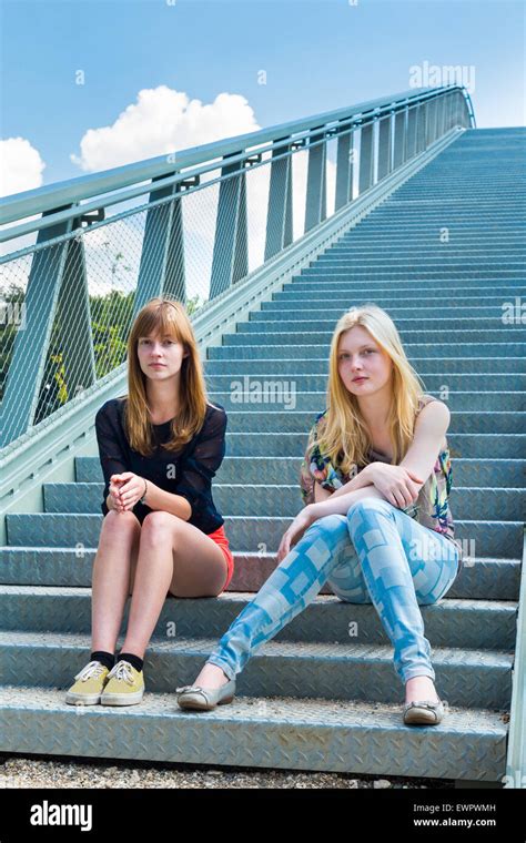 Two Caucasian Girls Sitting On Metal Bridge Stock Photo Alamy