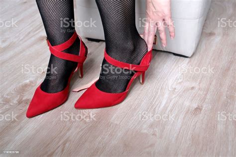 Woman In Black Fishnet Stockings Trying On Red Shoes On High Heels