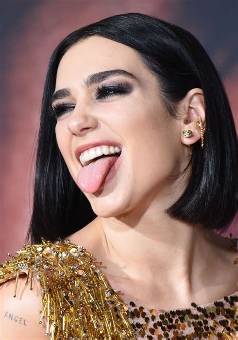 A Close Up Of A Person With Her Tongue Out And Wearing Gold Jewelry Smiling