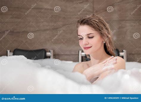 Attractive Blonde Woman Lying In Bathtub In Foam In Hotel Stock Image