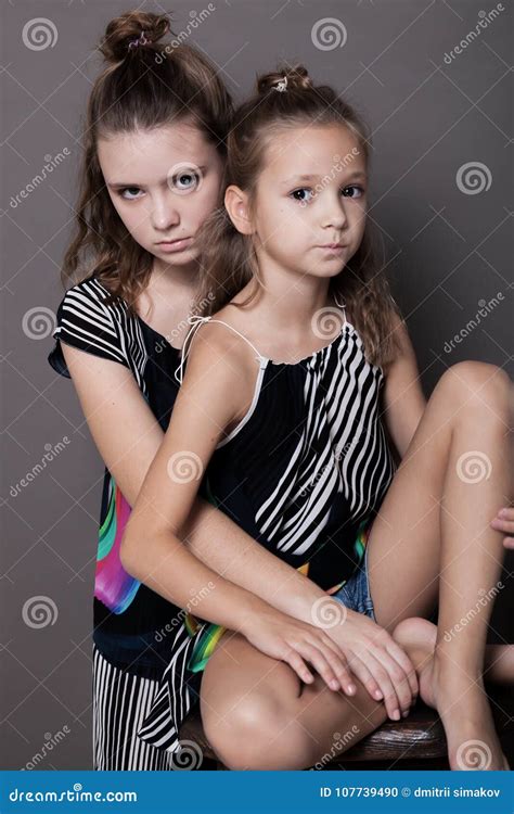 Twee Meisjeszusters Zij Aan Zij Op Een Grijze Achtergrond Stock Foto