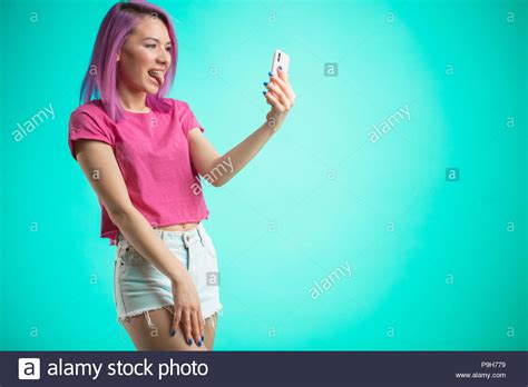 Cute Woman With Trendy Pink Hairstyle Dressed In Pink T Shirt Showing Tongue Making Selfie On