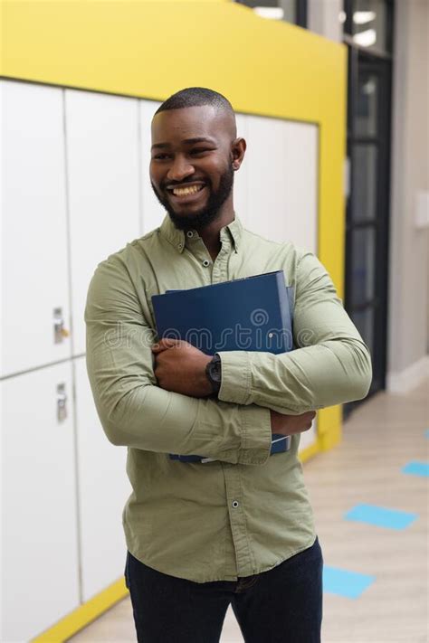 Smiling African American Young Male Teacher With Files Looking Away