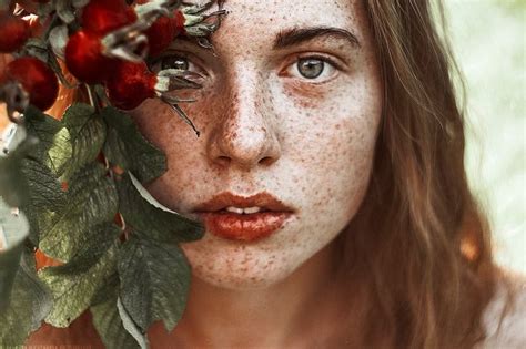 A Woman With Freckles On Her Face Holding Flowers In Front Of Her Face