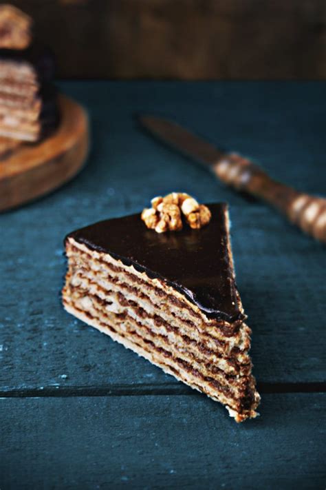 A Piece Of Chocolate Cake With Walnuts On Top And A Knife Next To It