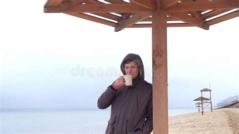Romantic Young Man Relaxing On The Beach With Drinking Hot Tea Or