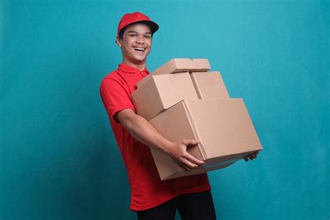 Repartidor asiático alegre que sostiene la pila de cajas de cartón