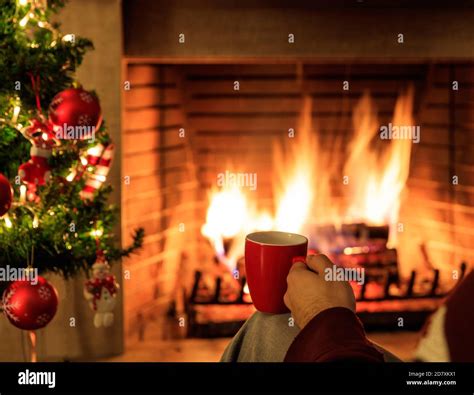 Man Holding A Red Cup Of Coffee Or Tea On Burning Fireplace Background