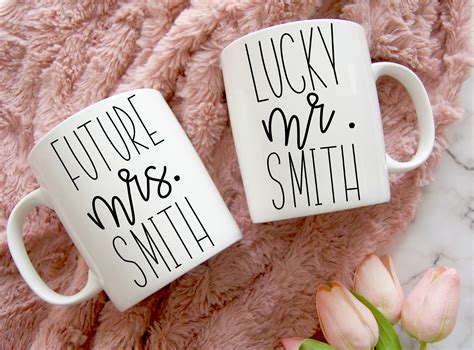 Two Coffee Mugs Sitting On Top Of A Pink Blanket