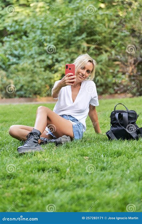 Young Woman Taking Selfies With A Mobile Phone While Sitting On Grass