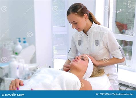 Cosmetologist Preparing Face To The Procedure Of Young Woman Lying On A