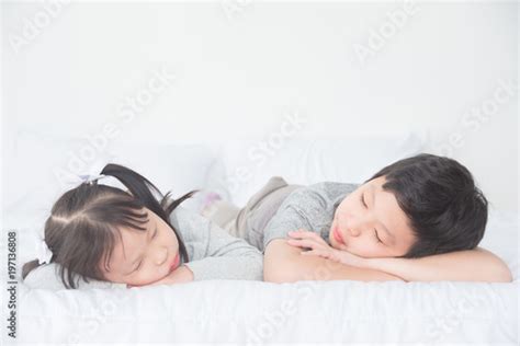 Two Asian Siblings Fall Asleep On Bed In Day Time Buy This Stock