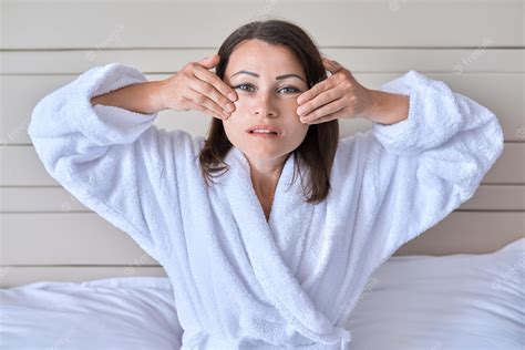 premium photo anti aging face massage beautiful mature woman in white bath robe doing facial