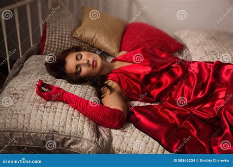 sinnlig brunett i en röd klänning som ligger på sängen arkivfoto bild av person budoar 58865234