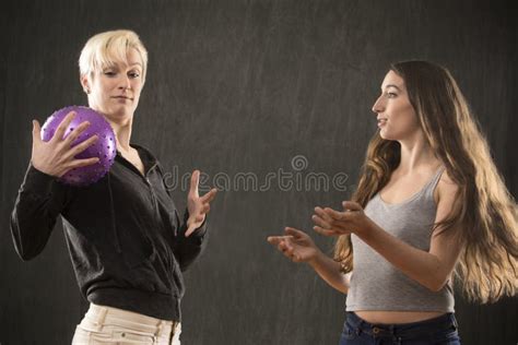 Two Young Women Playing With Purple Ball In The Studio Stock Image