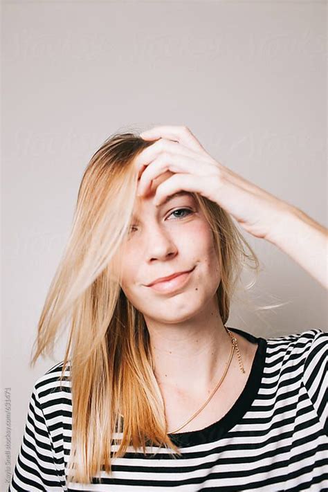 Young Blonde Woman Smiling And Fixing Her Hair By Kayla Snell For