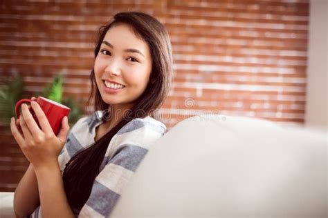 Smiling Asian Woman On Couch Having Hot Drink Stock Image Image Of Pretty Life 61440445