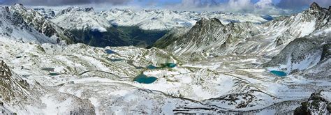 An Aerial View Of Snow Covered Mountains With Blue Lakes In The