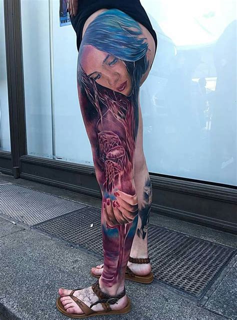 A Woman With Blue Hair And Tattoos On Her Leg Standing In Front Of A