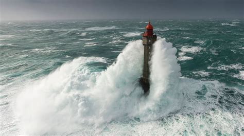 dramatic photos as massive waves completely engulf lighthouse in huge storms world news