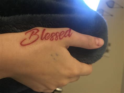 a woman's hand with a small tattoo on her left wrist that reads, blessed