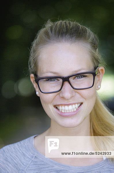 Nahaufnahme einer jungen Frau mit dicker Brille Portrait lächelnd