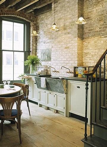 A white corian work top wraps around grey silk finished lacquered cupboard doors and draws. loft & cottage: exposed brick in the kitchen