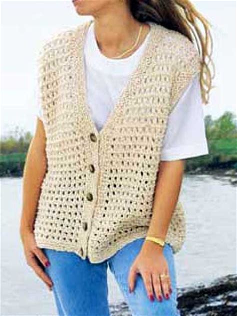 A Woman Is Standing By The Water Wearing A Crocheted Vest With Buttons