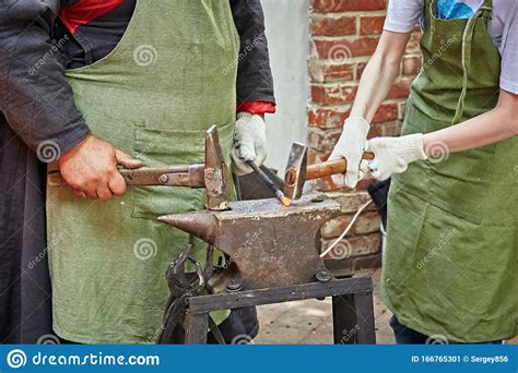 Two Blacksmiths An Experienced One And His Apprentice Stock Image