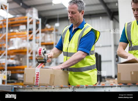 Men Packing Cardboard Box In Warehouse Stock Photo Alamy