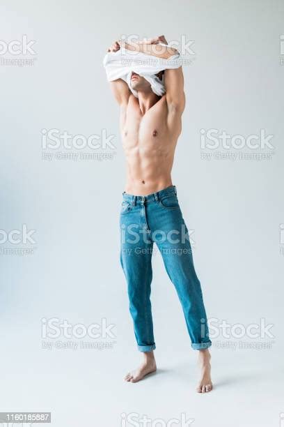 흰색 티셔츠를 벗고 흰색에 서있는 동안 얼굴을 덮고있는 근육질의 남자 옷 벗기에 대한 스톡 사진 및 기타 이미지 옷 벗기