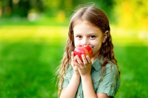 Premium Photo Happy Baby Girl In Summer On The Lawn With A Red Apple