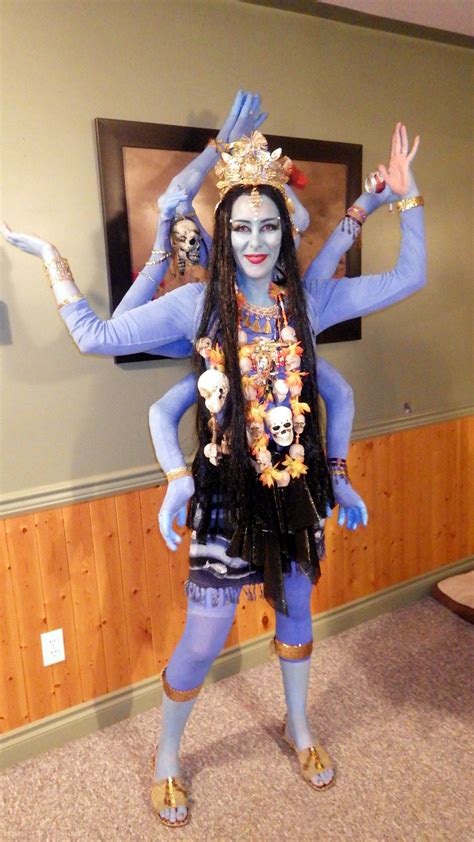 A Woman Dressed In Blue And Gold Poses For The Camera With Her Hands Up While Wearing An