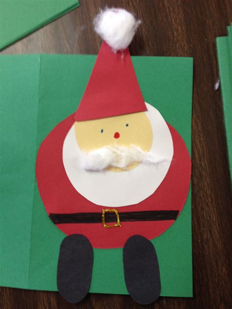 A Paper Santa Clause On Top Of A Green Piece Of Paper Next To Some Scissors