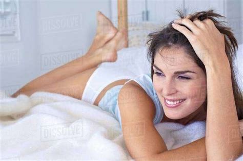 Woman Smiling And Laying On A Bed Stock Photo Dissolve