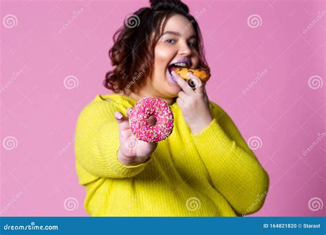 Cheerful Plus Size Model Eating Doughnuts Fat Woman Overeats On Pink Background Stock Photo