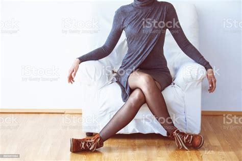 Woman In Gray Dress Sitting Legs Crossed On Armchair Stock Photo