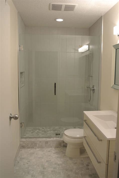 A Bathroom With A Walk In Shower Next To A White Toilet And Sink Under