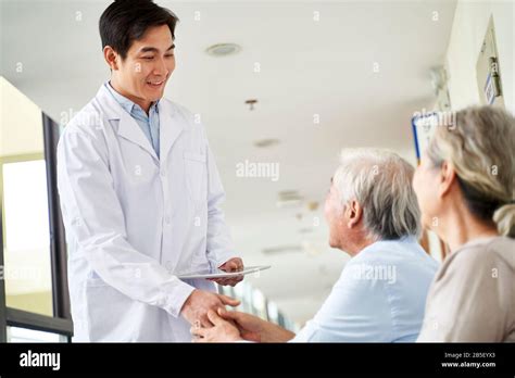 Friendly Young Asian Doctor Coming To Waiting Area Shaking Hands With