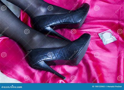 Female Legs In Stockings On Pink Cloth A Condom Lies Next To It Sex Protection Concept