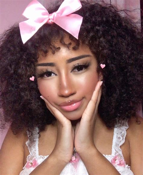 A Woman With Long Curly Hair Wearing A Pink Bow And Holding Her Hands