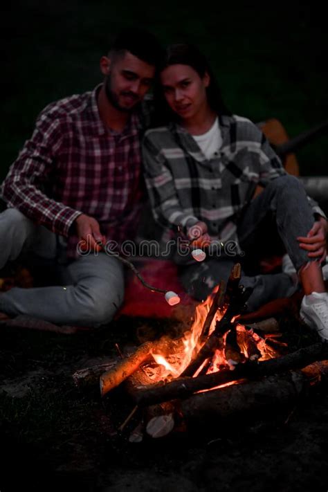 Happy Couple Roasting Marshmallows On Campfire On Nature Stock Image