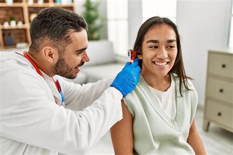 Doctor Examining Latin Woman Ear Using Otoscope At Clinic Stock Image