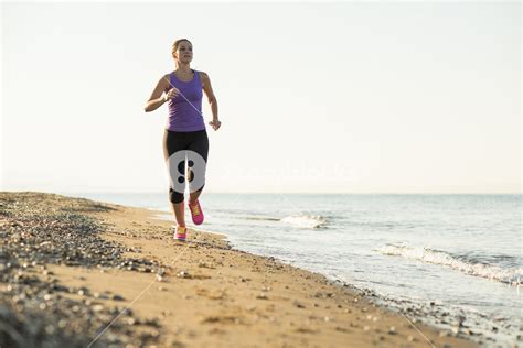 Young Woman Is Running In Sunny Nature Along The Beach Royalty Free
