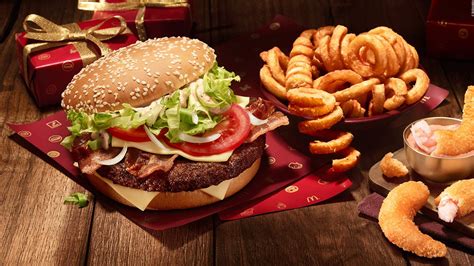 A Hamburger French Fries And Onion Rings On A Wooden Table With Red