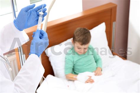 Doctor Adjusting Intravenous Drip For Little Child In Hospital Closeup