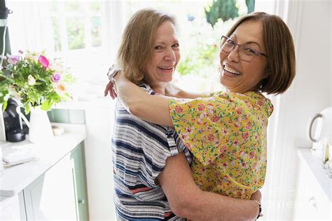 Senior Lesbian Couple Hugging In Kitchen Photograph By Caia Image