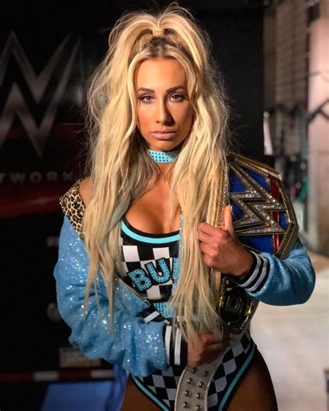 A Woman With Long Blonde Hair Wearing A Wrestling Outfit And Holding A Belt In Her Hand
