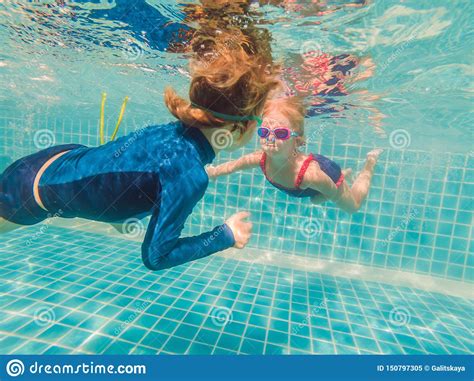 Kids Having Fun Playing Underwater In Swimming Pool On Summer Vacation