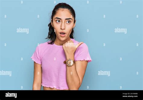 Hispanic Teenager Girl With Dental Braces Wearing Casual Clothes Surprised Pointing With Hand